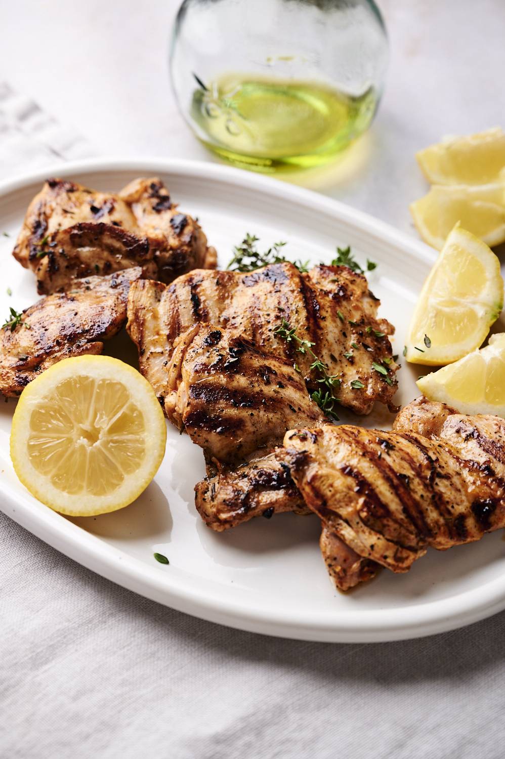 Grilled lemon paprika chicken thighs on a plate with lemon slices and fresh thyme.