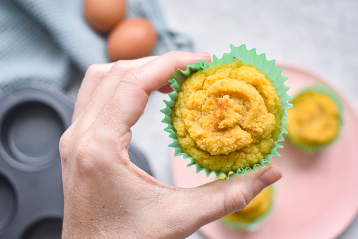 Coconut flour muffins being held up by a hand.