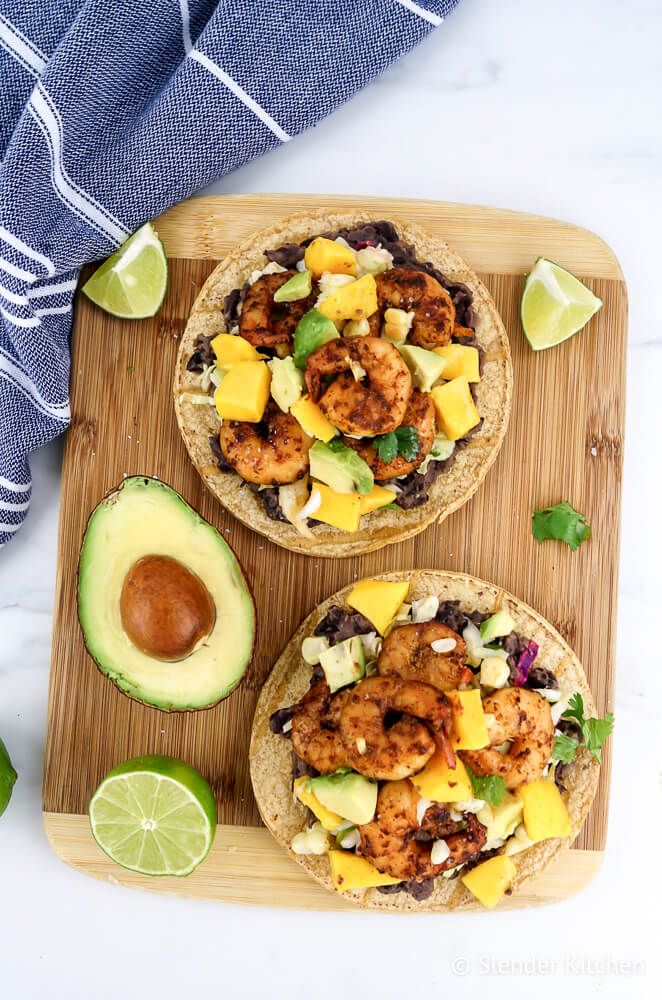 Shrimp Tostadas with Mango Salsa on a cutting board with limes and avocado.