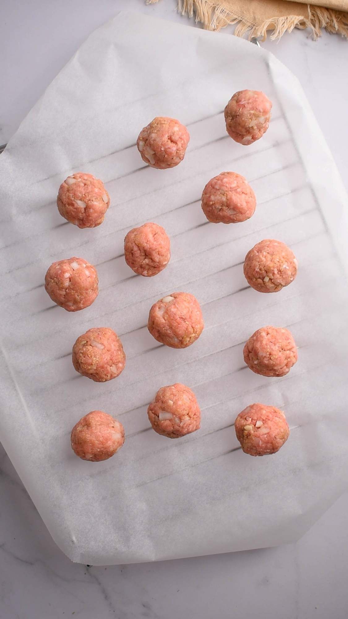 Chipotle meatballs with ground beef, onion, and herbs on a wire rack with parchment paper.