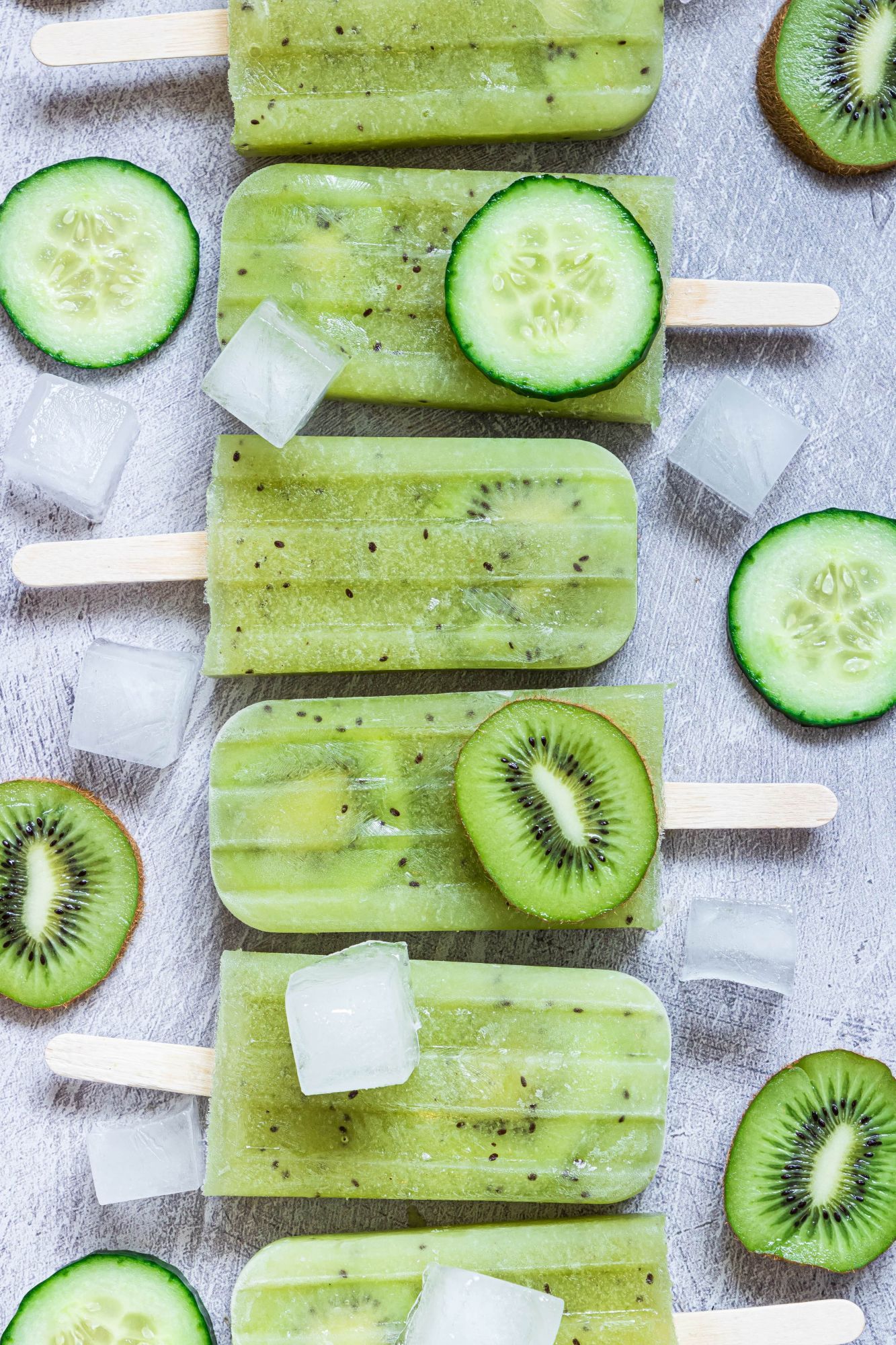 Cucumber popsicles with fresh kiwi frozen on a board with cucumber slices.