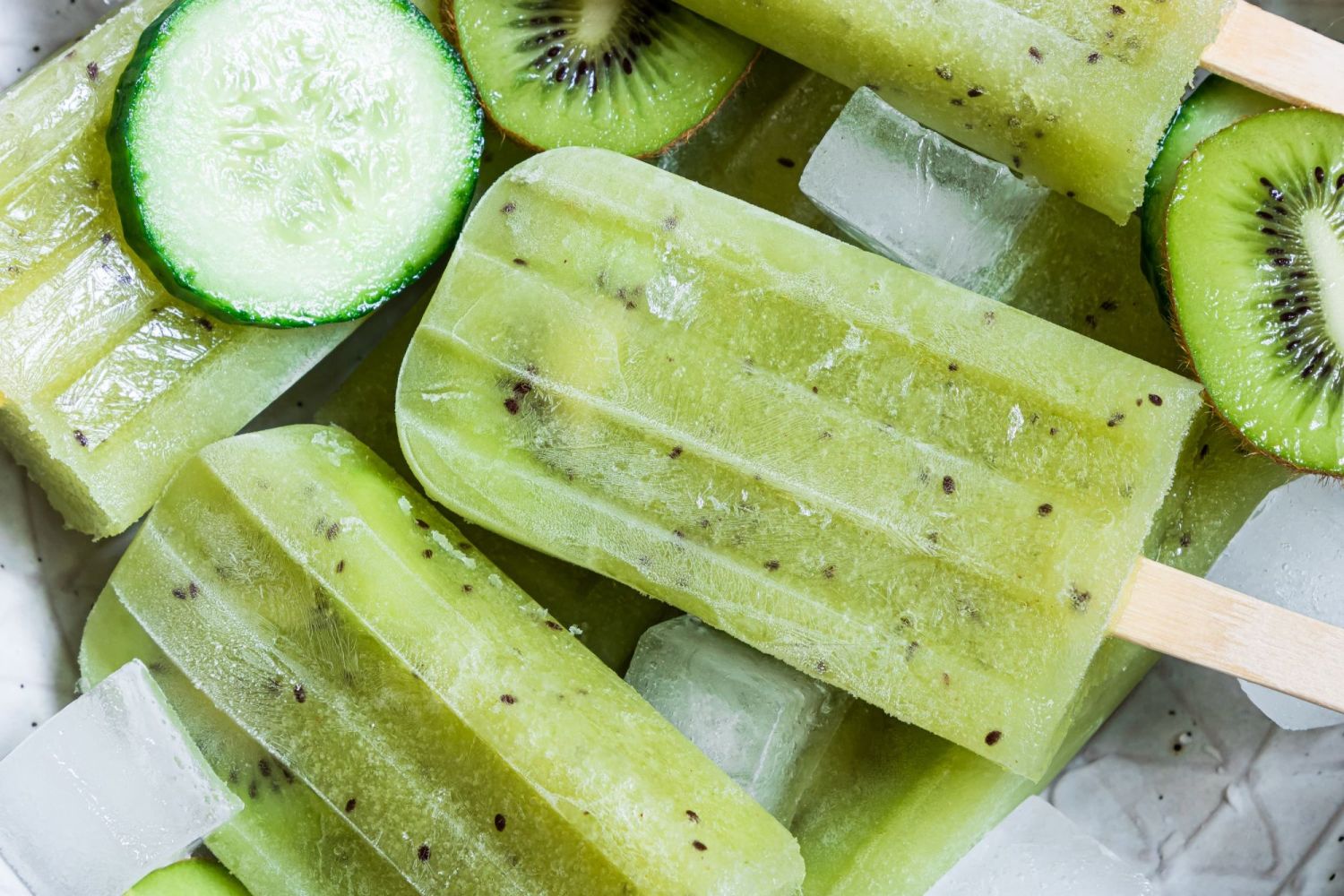 Cucumber paletas with kiwi slices and kiwi seeds made with wooden popsicle sticks.