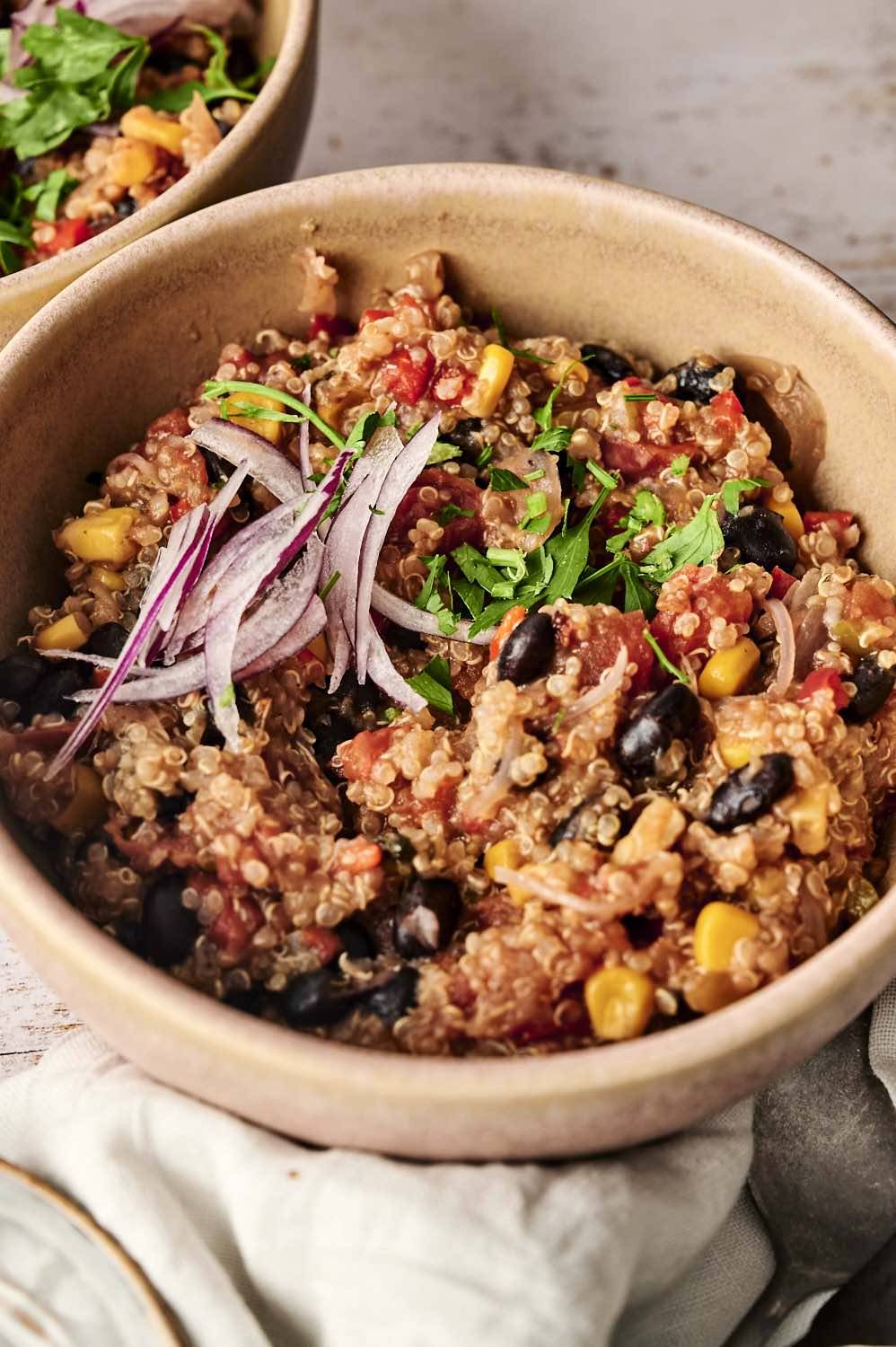 Mexican quinoa bowl topped with fresh cilantro and thinly sliced red onions, ready to enjoy.