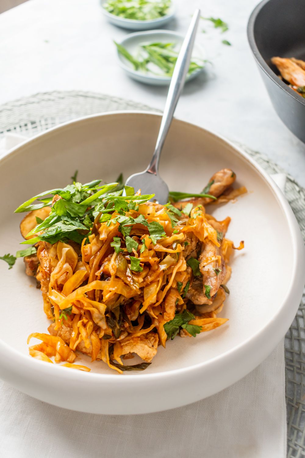 Moo shu stir fry with pork tenderloin, cabbage, carrots, and mushrooms in a bowl with herbs.