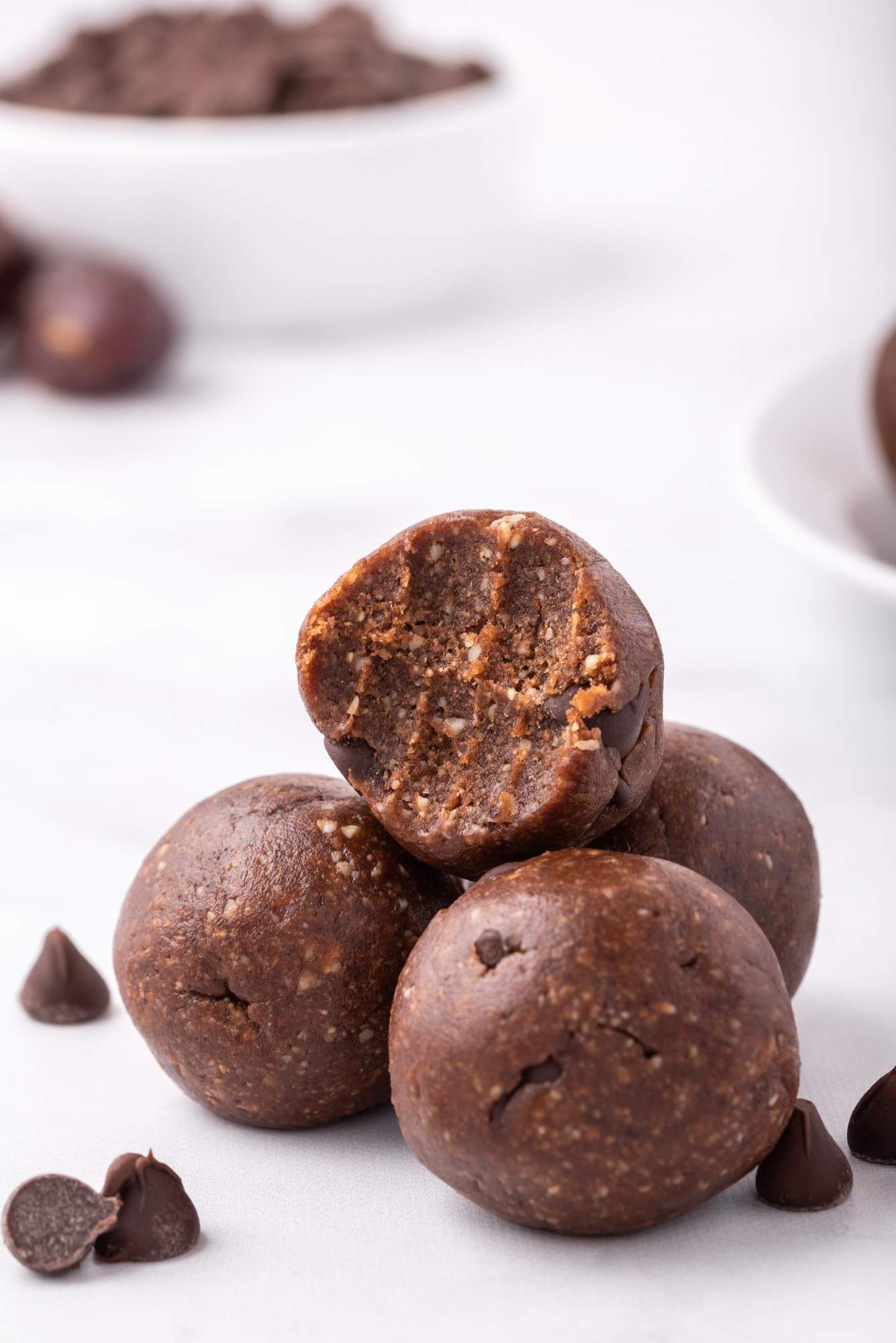No bake healthy brownie bites made with dates, nuts, and unsweetened cocoa in a small pile with chocolate chip.