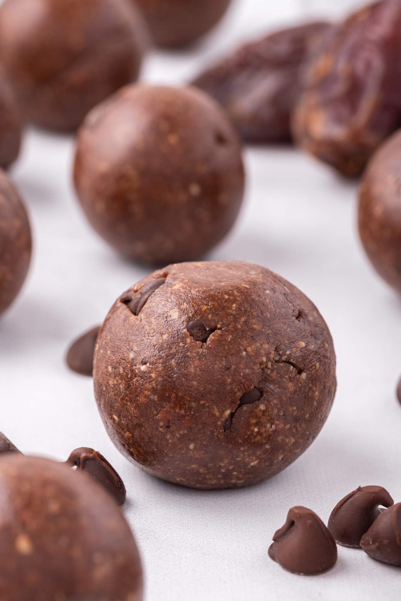 Date brownie bites rolled in small balls with dates, cashews, almonds, and chocolate chips on a plate.