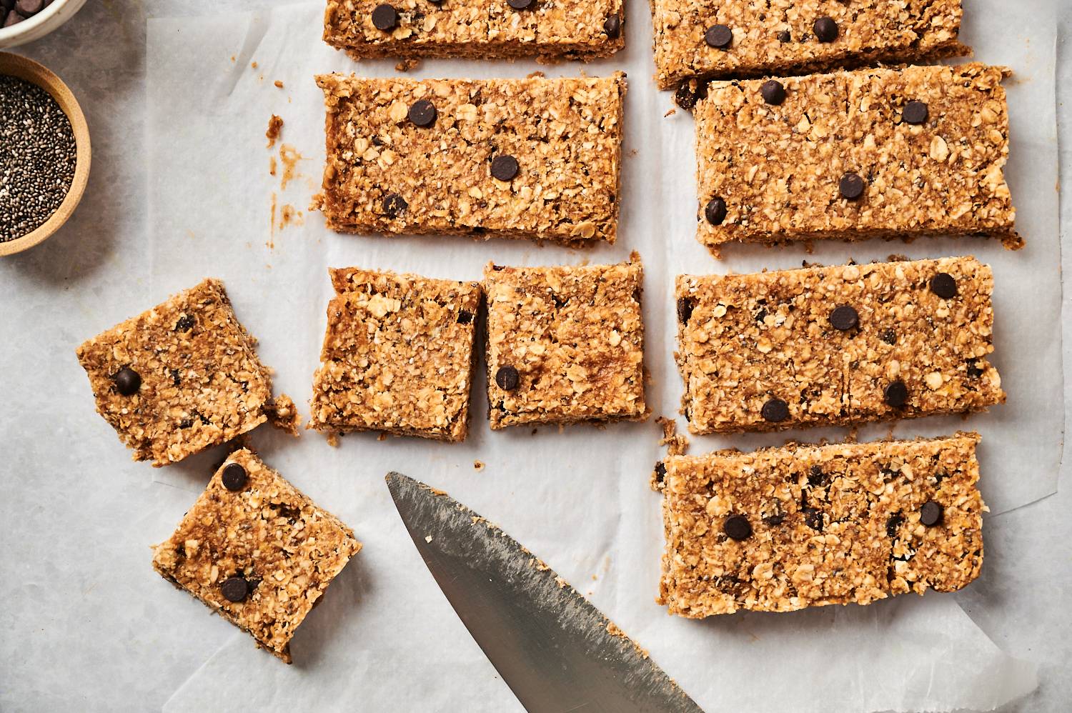 No bake chocolate peanut butter oat bars being cut into squares with a knife.