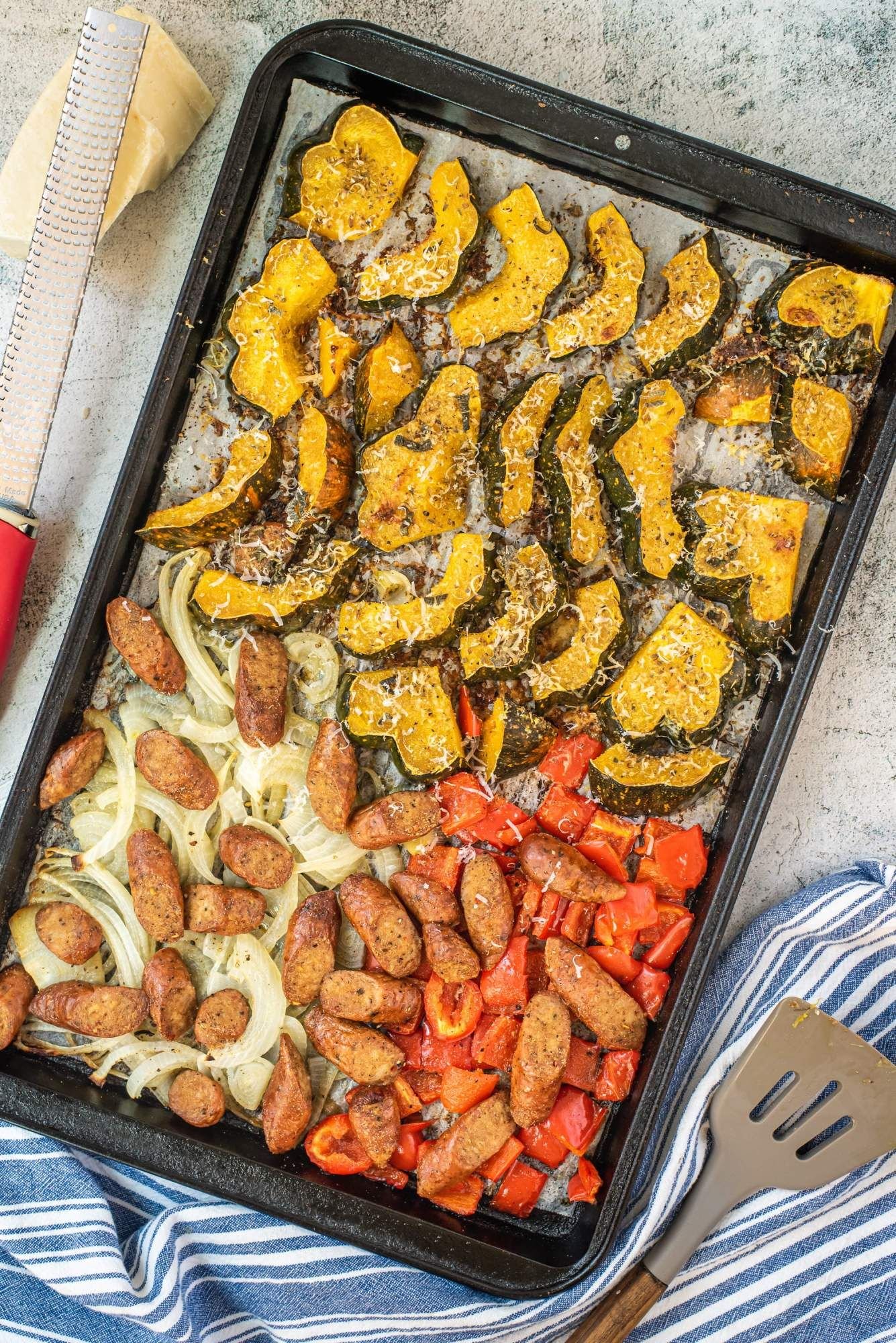 Sheet pan sausage and vegetables with peppers, onions, and acorn squash on a sheet pan.