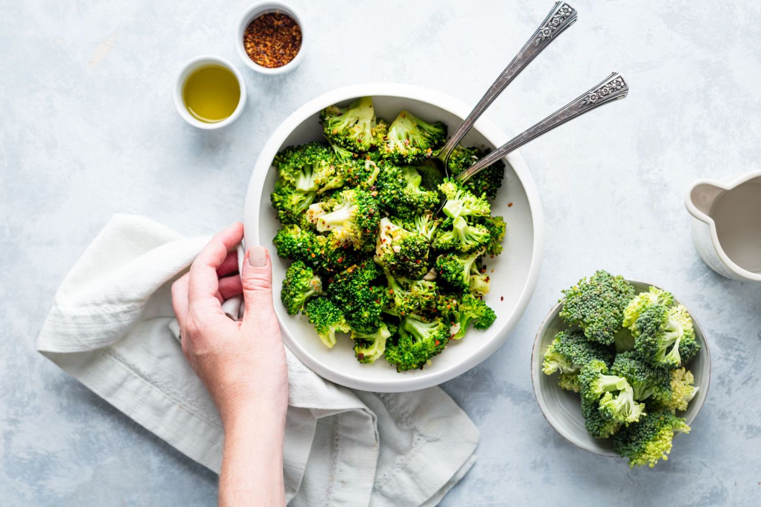Garlic pan fried broccoli florets in a bowl wit salt, pepper, and red pepper flakes.