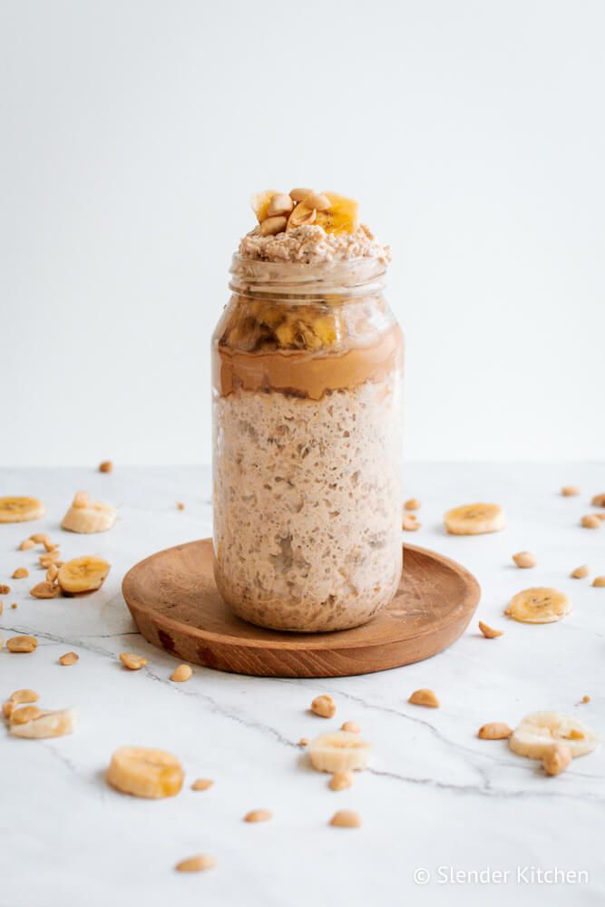 Banana overnight oats with peanut butter in a mason jar with fresh peanuts and bananas on the side.