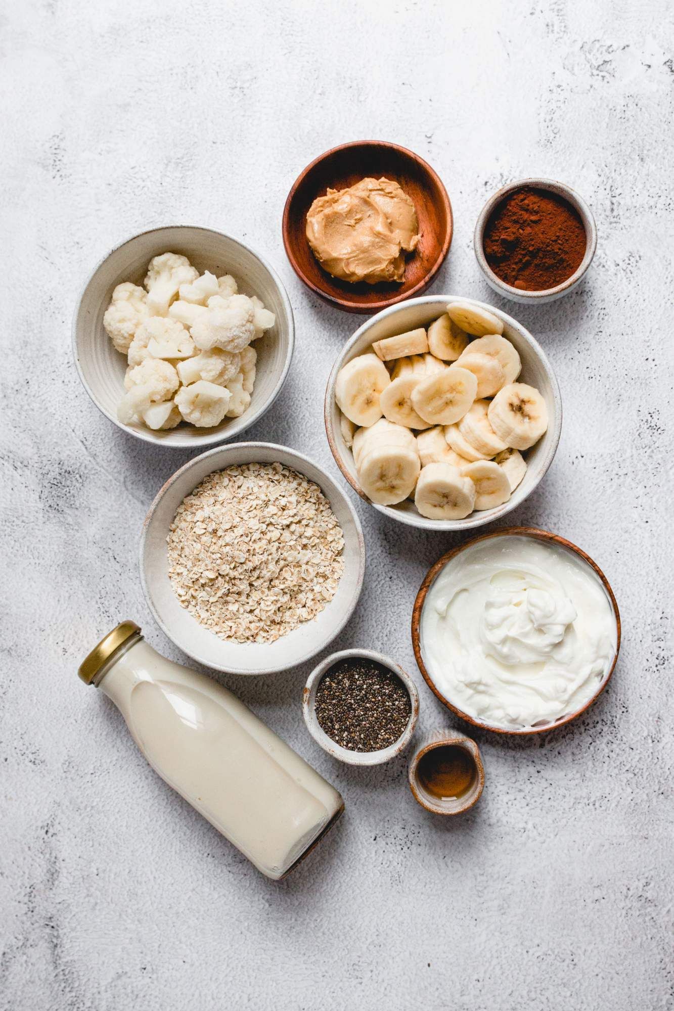 Ingredients for a peanut cup smoothie including frozen bananas, oatmeal, chia seed, peanut butter, and almond milk.