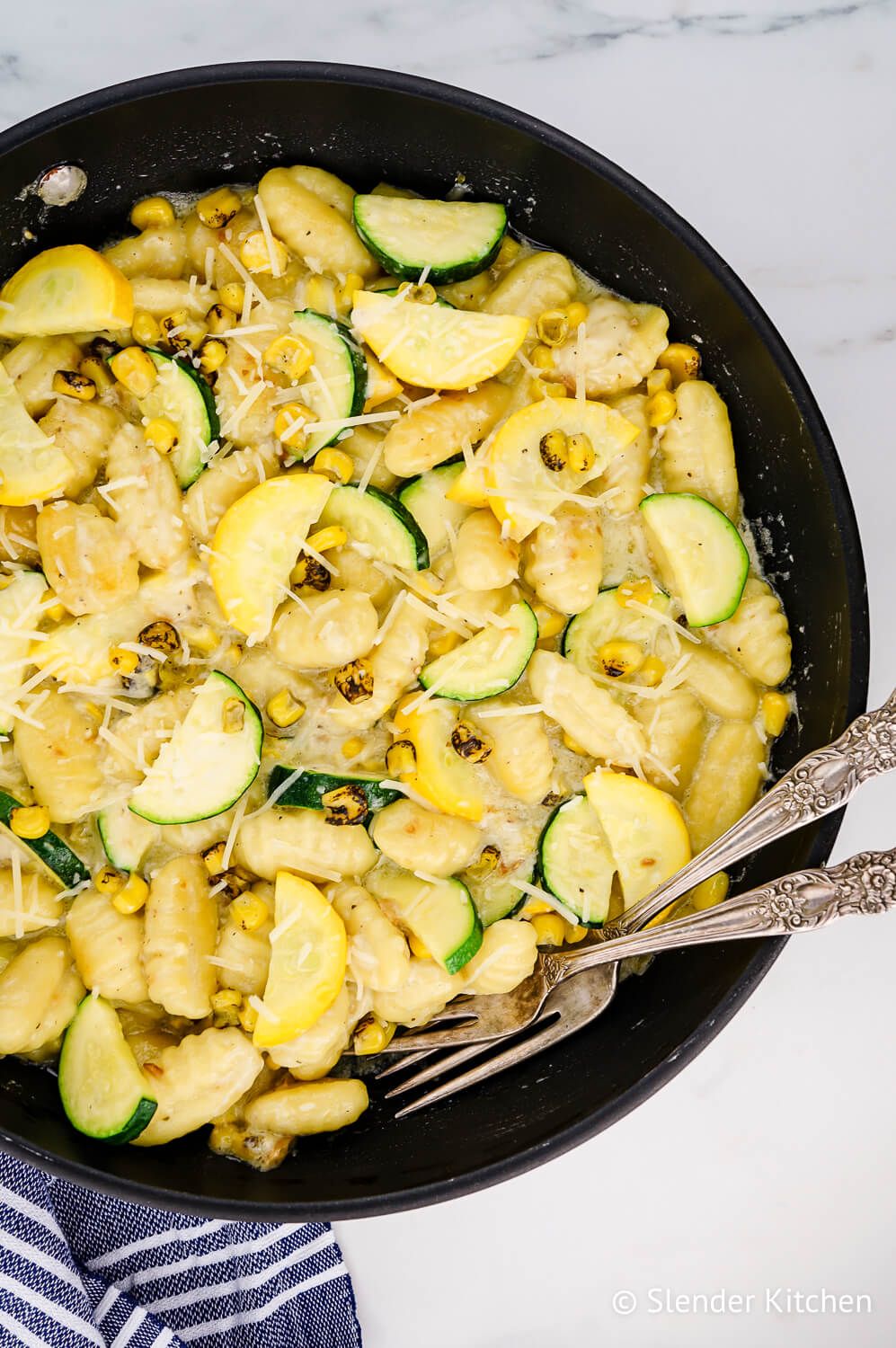 Potato gnocchi with zucchini and corn in a skillet.