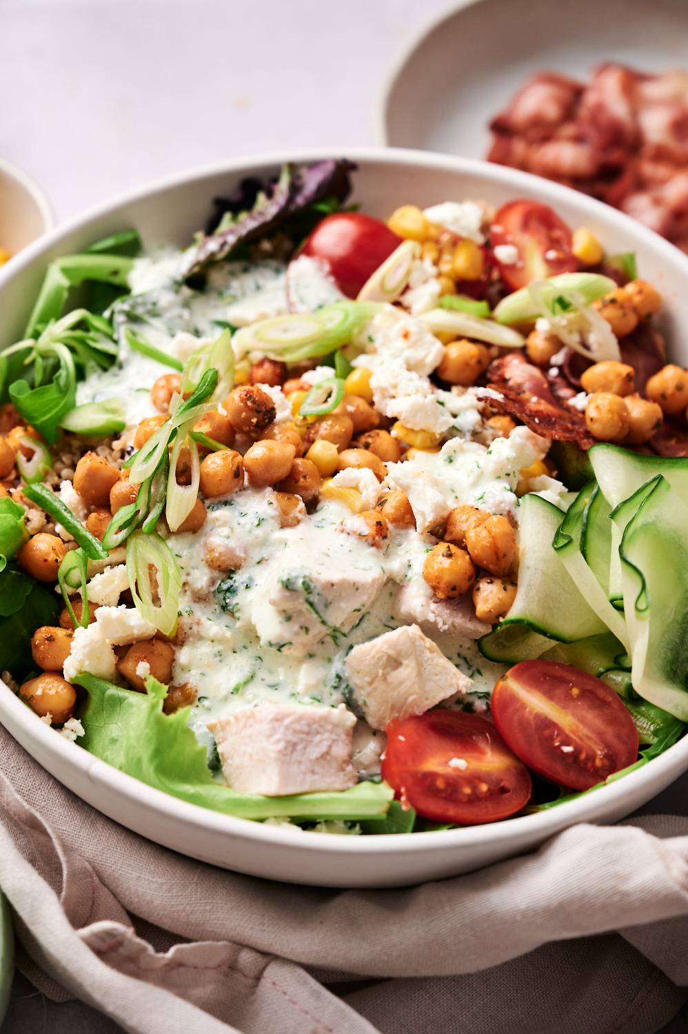 Protein salad power bowls with chicken breast, chickpeas, cucumbers, greens, tomatoes, goat cheese, and cottage cheese dressing.
