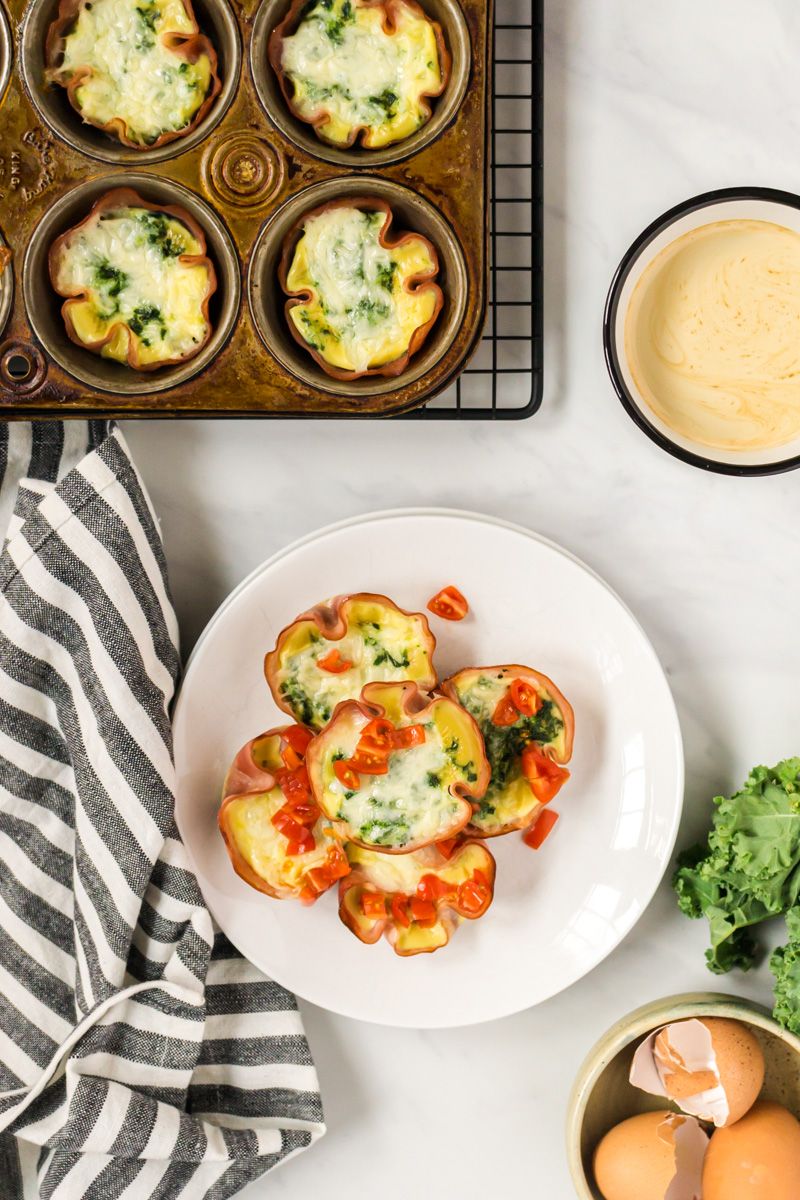 Ham quiche cupcakes with eggs, egg whites, ham, and spinach in a muffin tray and on a plate. 