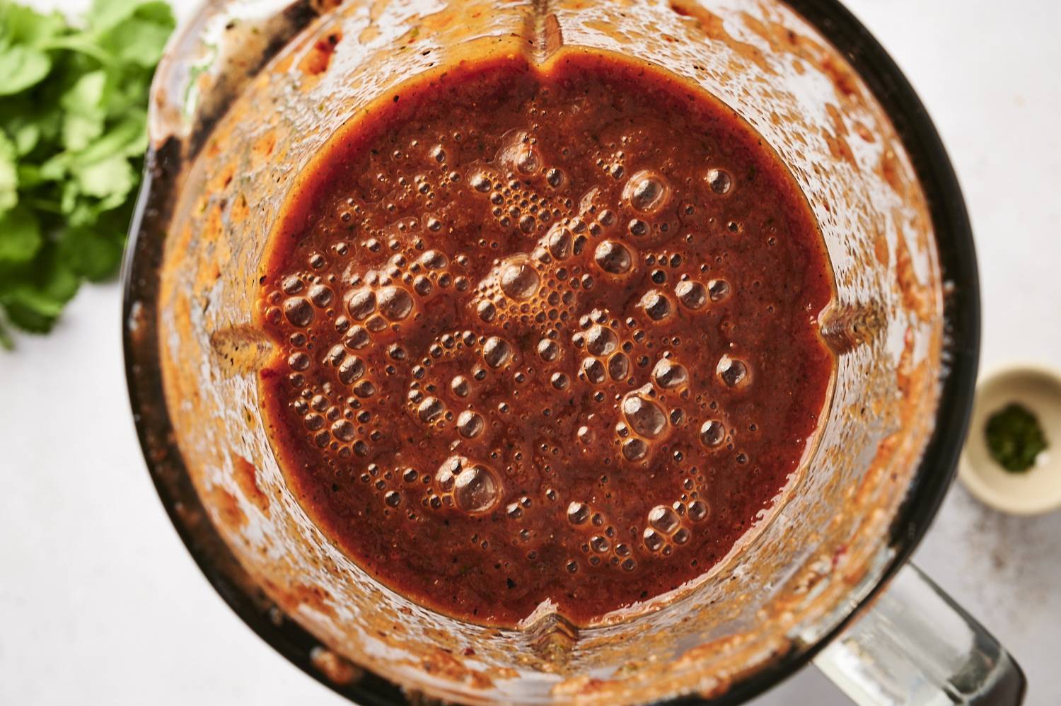 Freshly blended red enchilada sauce with a rich, bubbly texture in a blender jar.