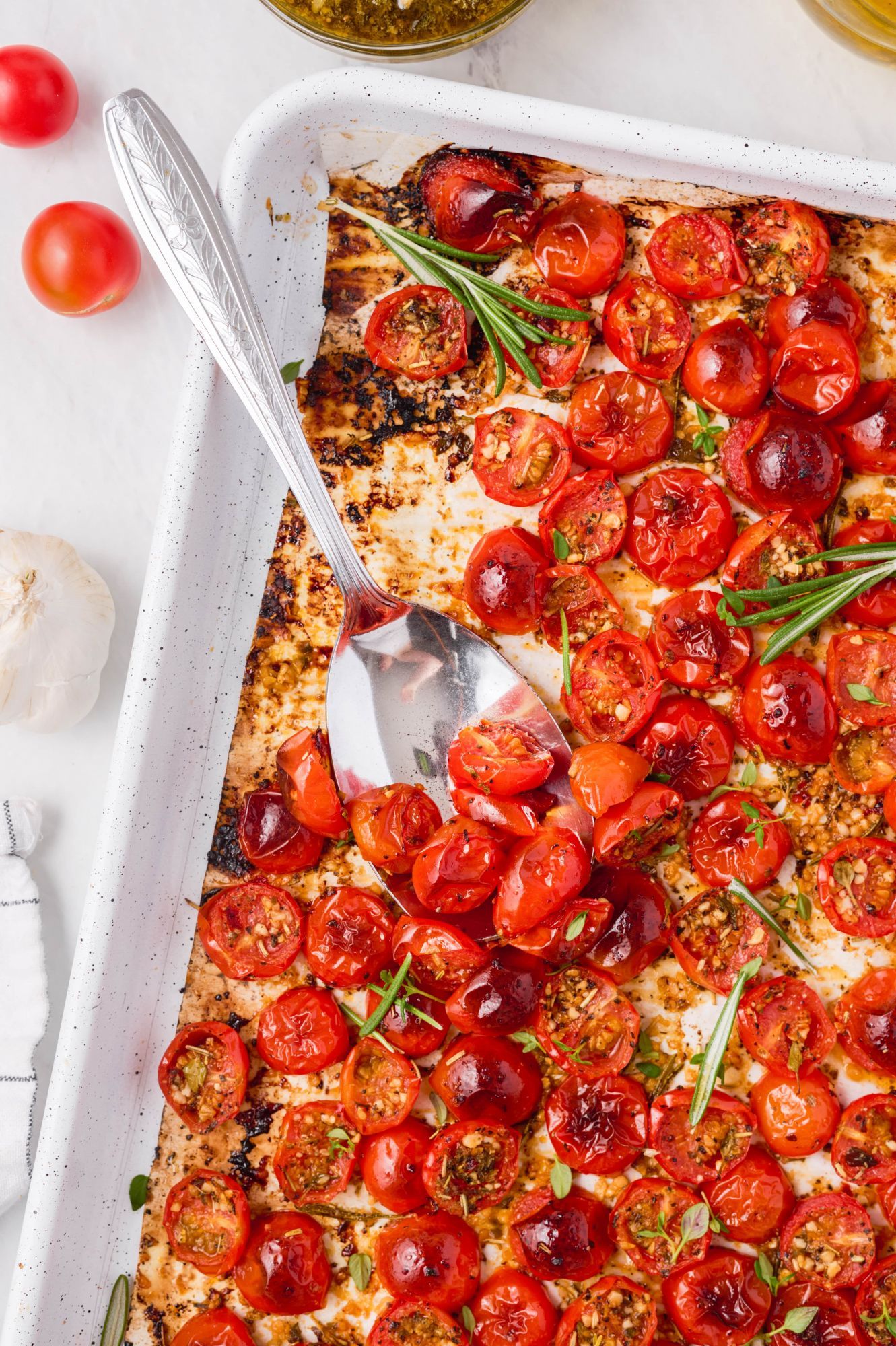 Cherry tomatoes roasted on a baking sheet with olive oil garlic, Italian seasoning, salt, and pepper.