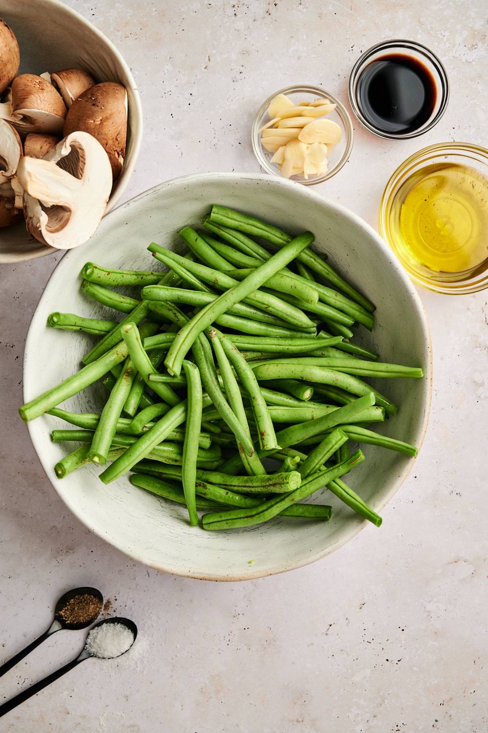 Ingredients for roasted green beans and mushrooms including fresh green beans, baby bella mushrooms, garlic, olive oil, salt, pepper, and balsamic vinegar.