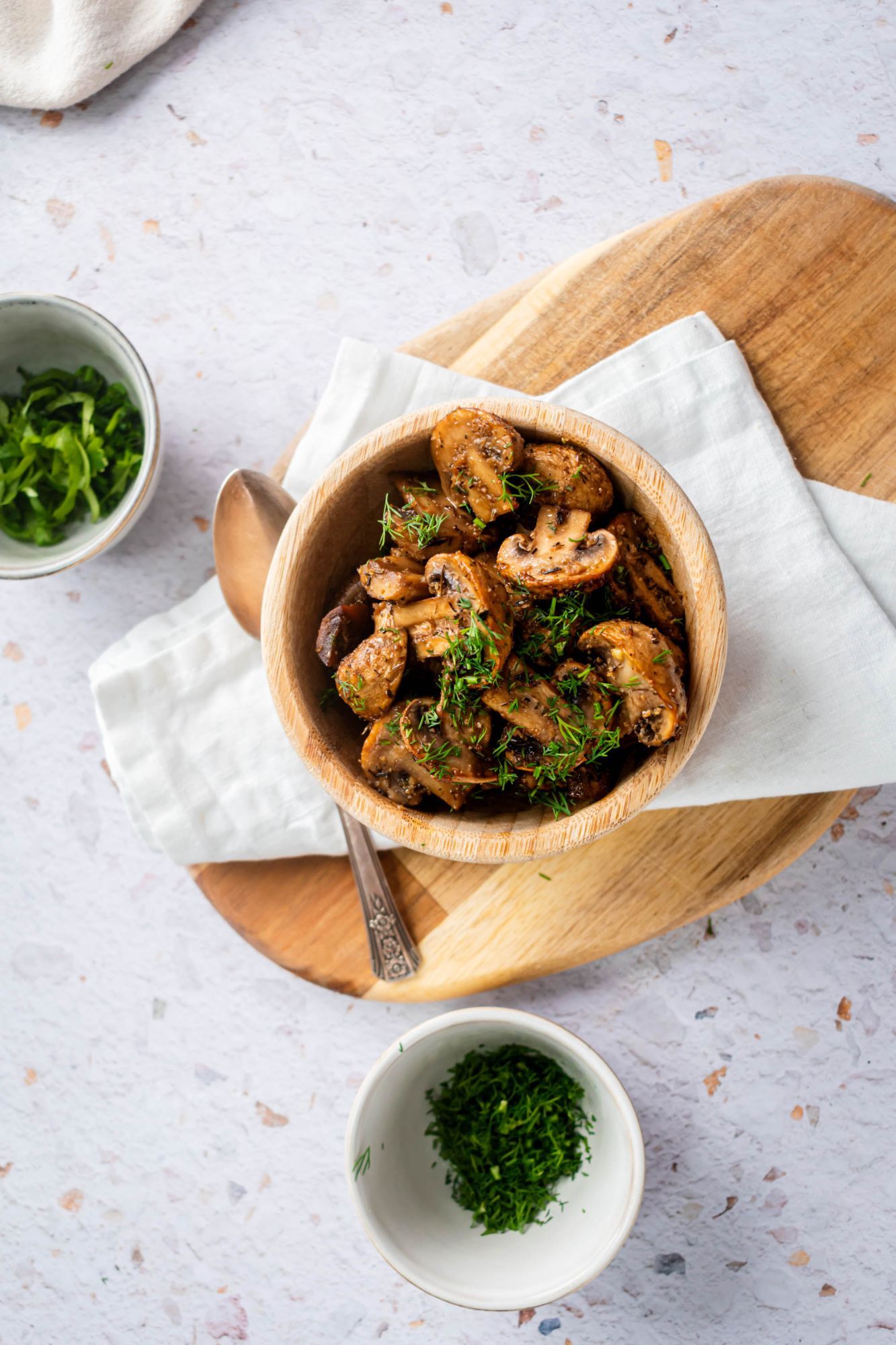 Balsamic roasted mushroom halves served in a bowl with fresh herbs.