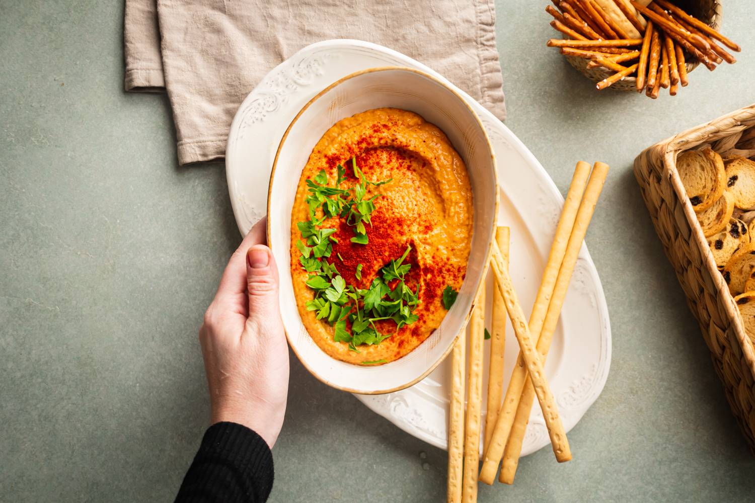 Creamy chickpea red pepper hummus served with breadsticks and crackers.