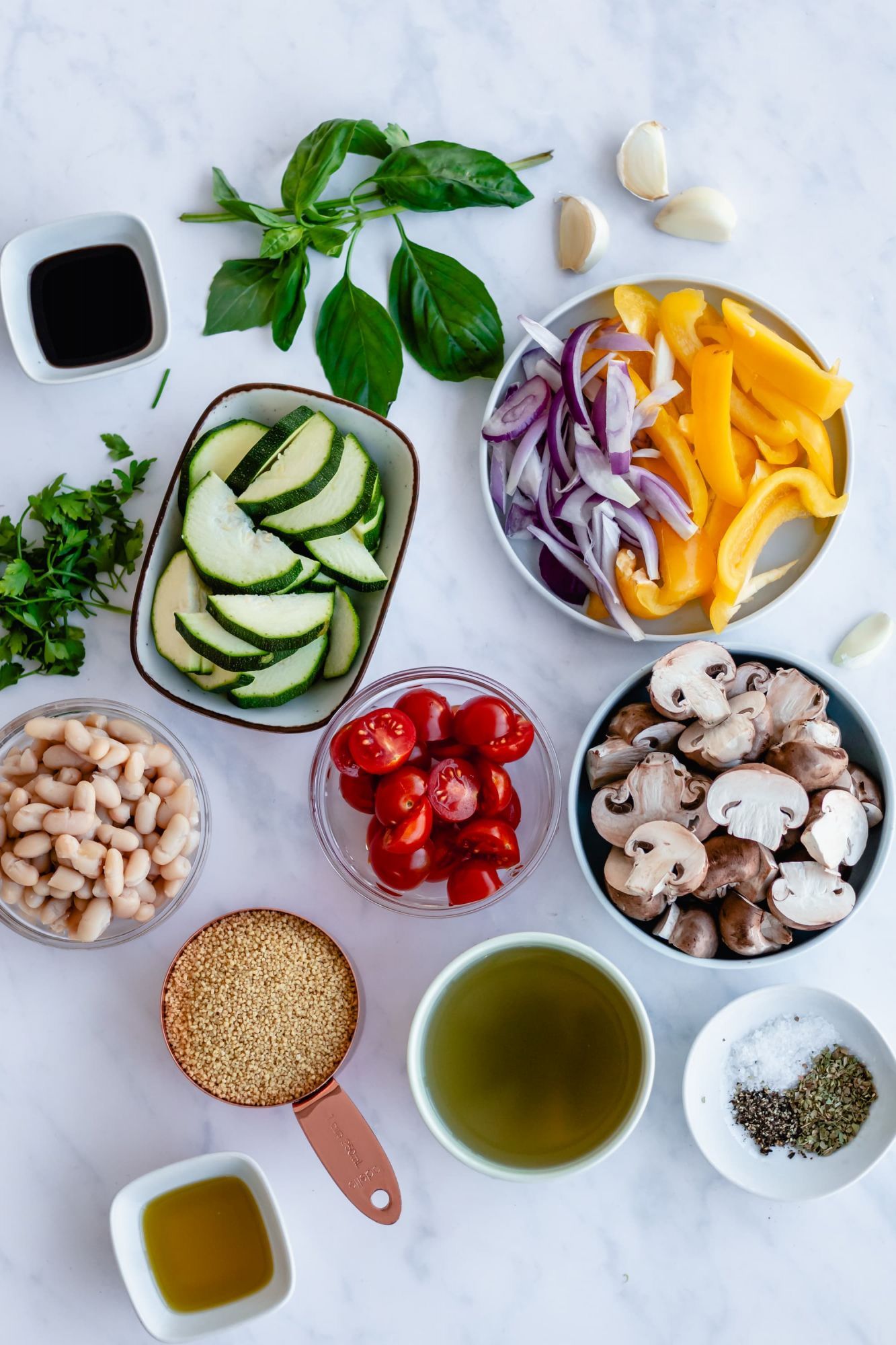 Ingredients for roasted vegetables with couscous including zucchini, peppers, onions, mushrooms, tomatoes, and couscous.