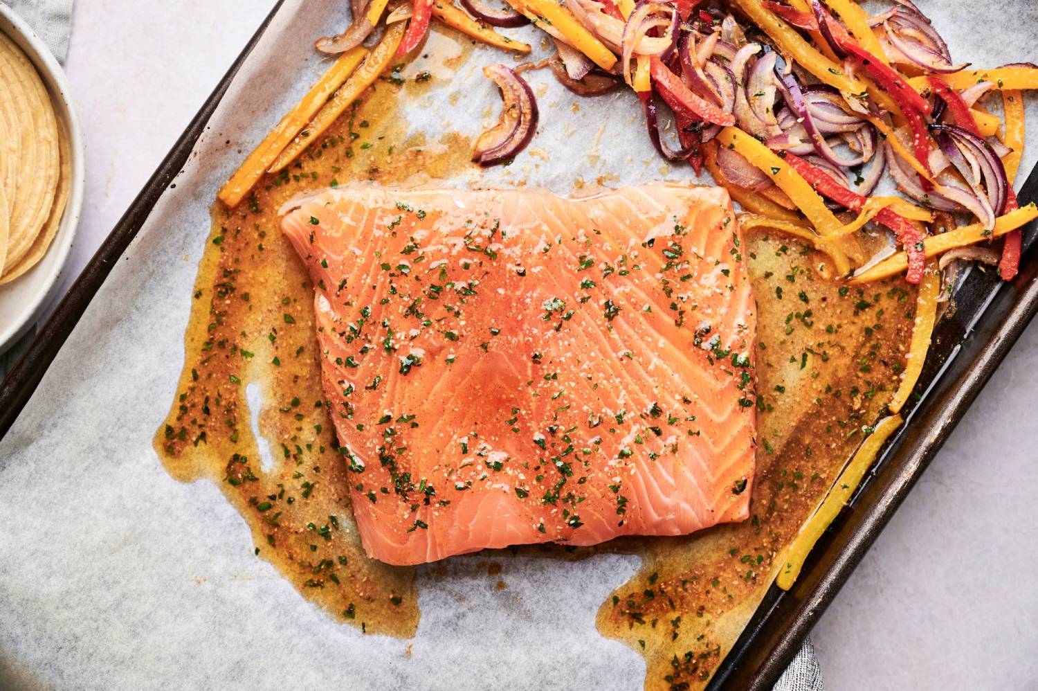 Fajita seasoned salmon on a sheet pan with roasted peppers and onions.