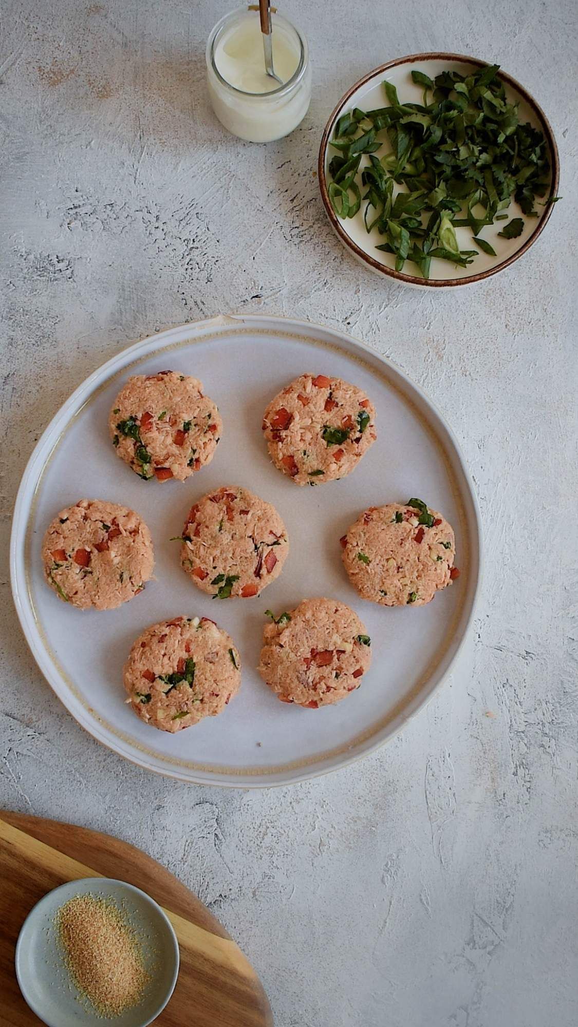 Homemade canned salmon patties with fresh herbs, red pepper, and spices formed into small patties.