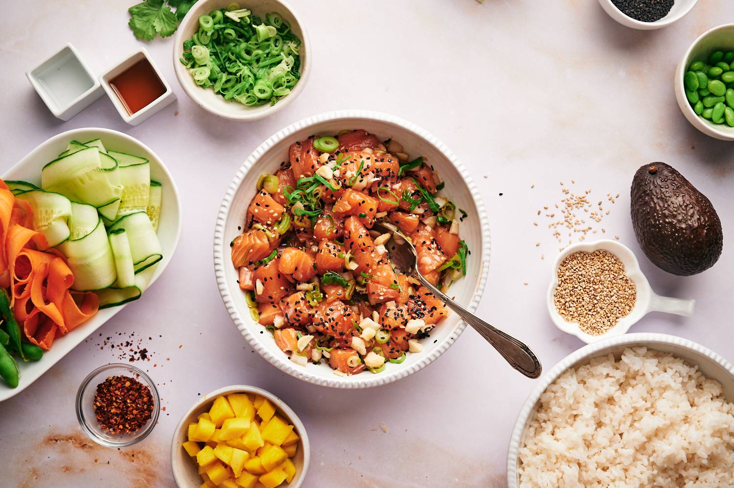 Salmon poke in a bowl with green onions, sesame seeds, soy sauce, and sesame oil.