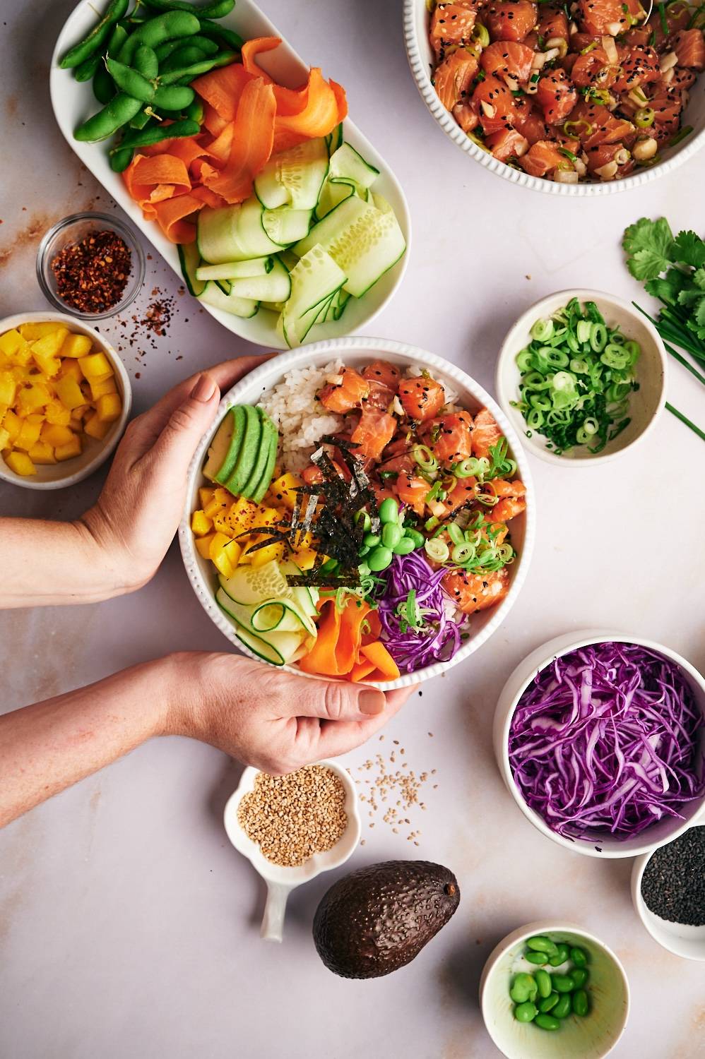 Poke bowls with raw salmon, white rice, edamame, avocado, edamame, seaweed, and veggies.