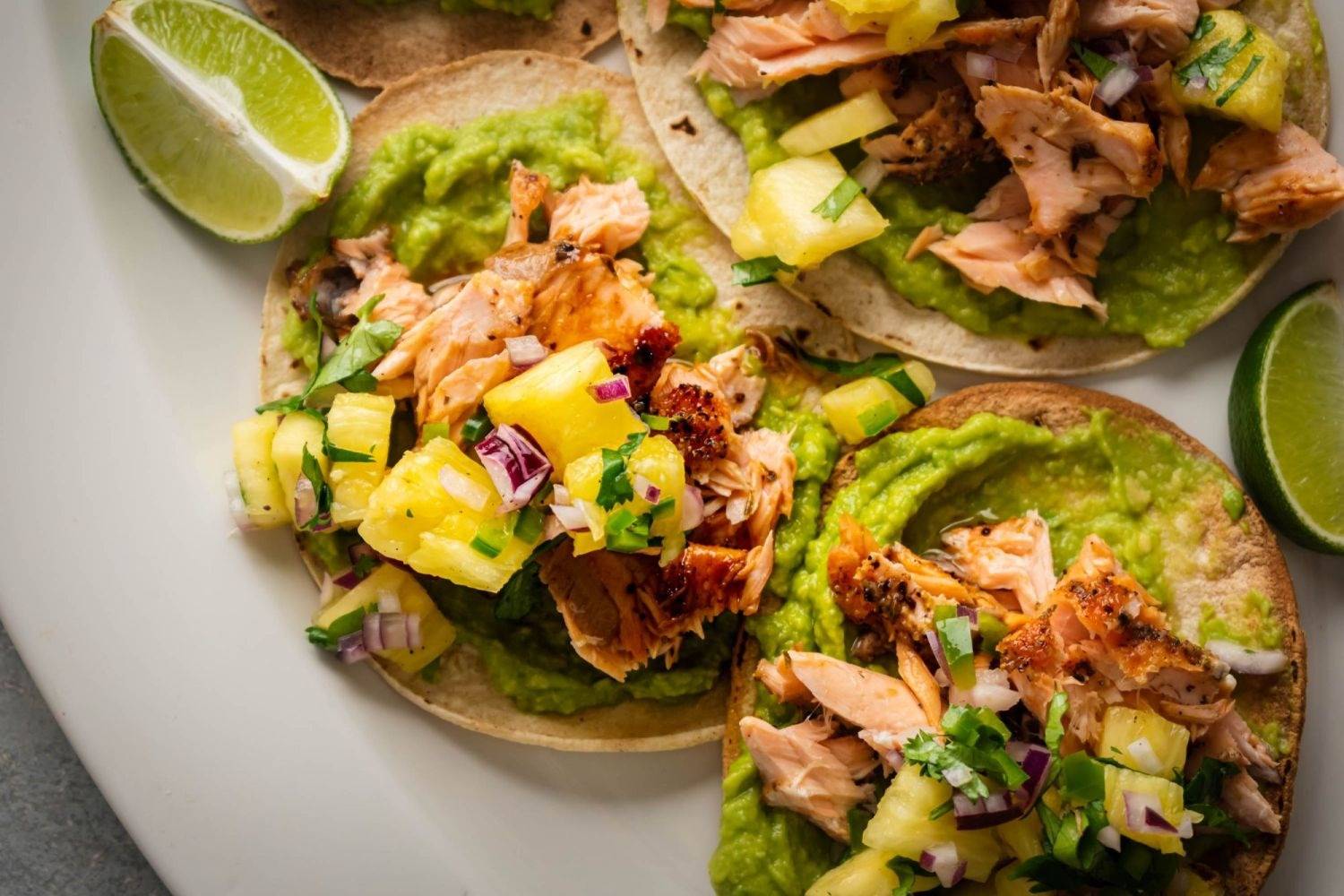 tostadas served with grilled salmon, pineapple salsa, coriander, red onion and creamy avocado on yellow tortillas.