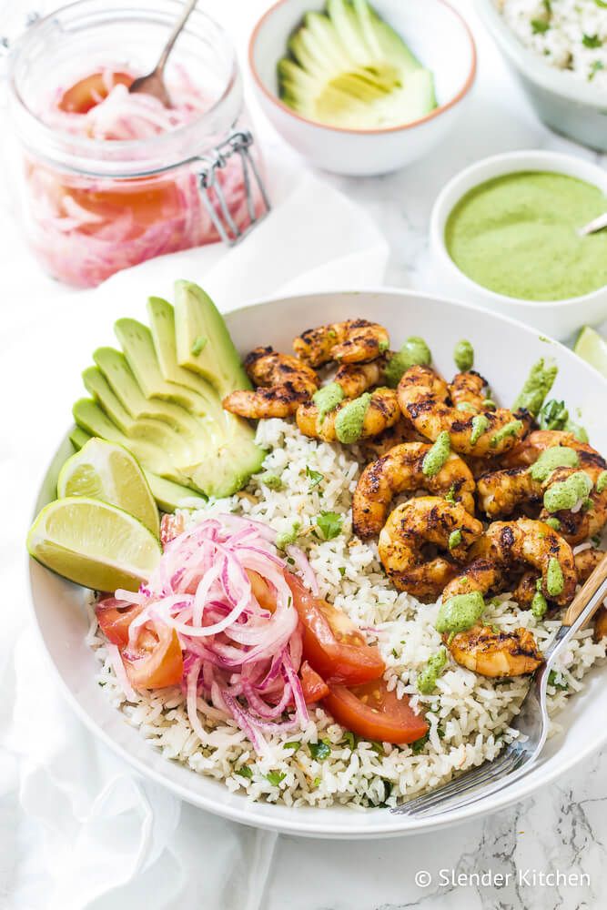 Rice bowl with salsa criolla and shrimp with a jar of pickled onions and tomatoes on the side.