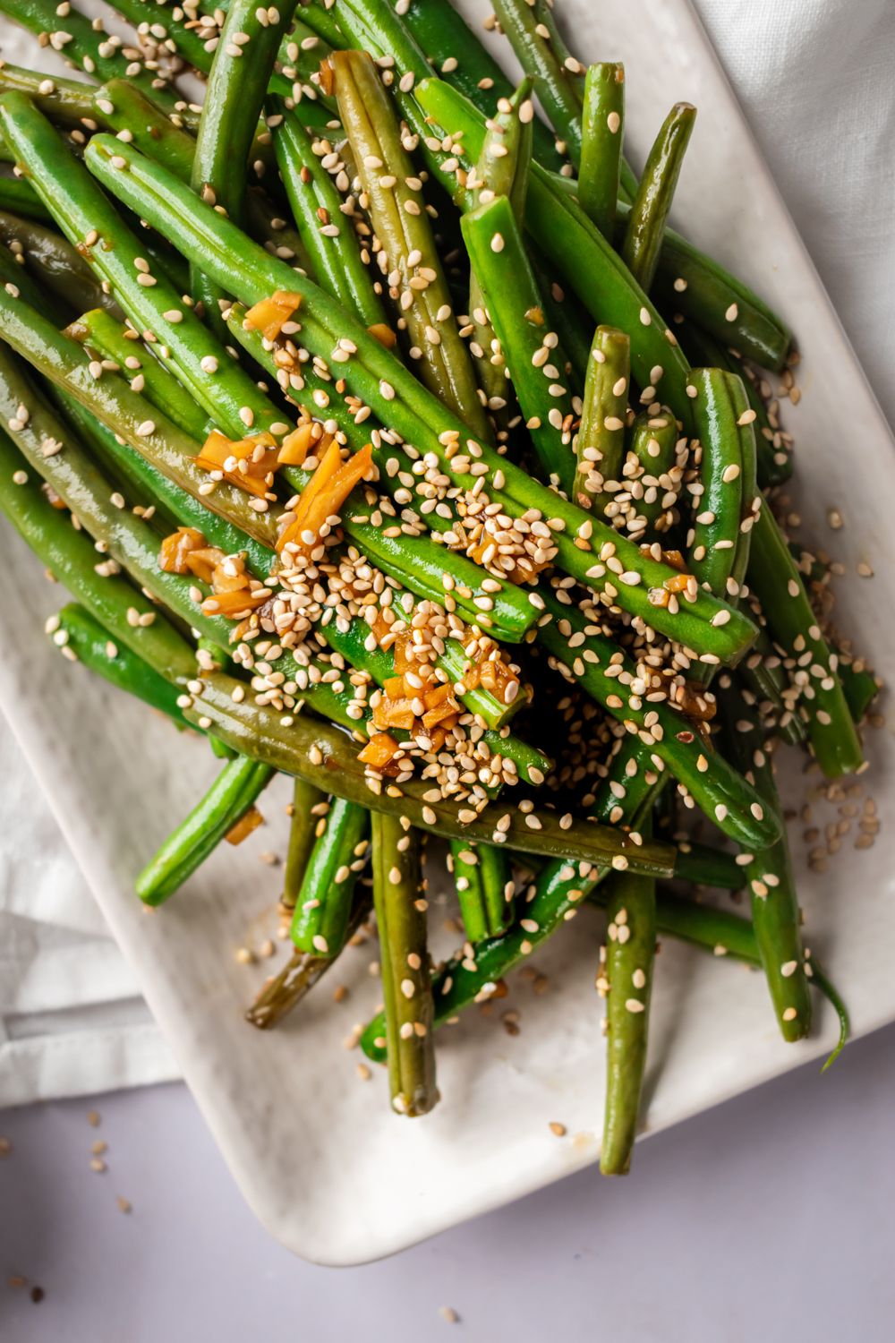 Asian green beans with sesame oil, sesame seeds, soy sauce, and garlic on a plate.