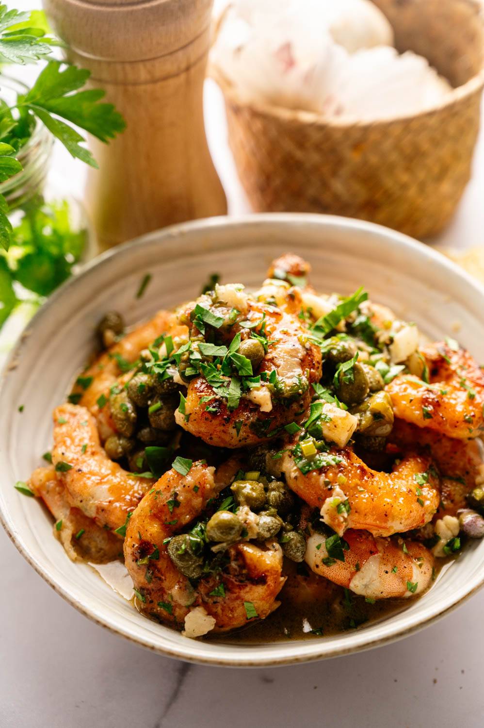 A bowl of cooked shrimp with capers, garlic, and parsley garnish, creating a vibrant and savory presentation. Cozy kitchen ambiance in the background.