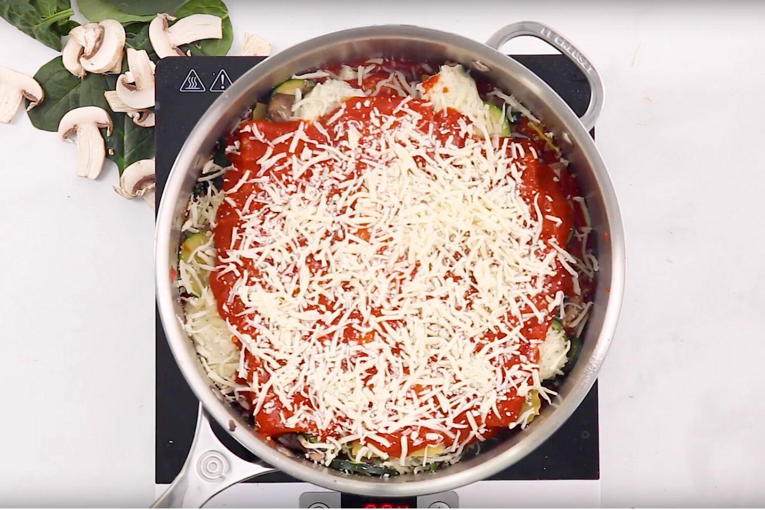 Skillet lasagna in a skillet with layers of noodles, vegetables, ricotta, mozzarella, and sauce.