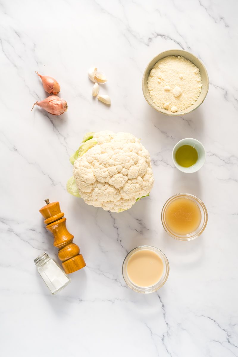 Ingredients for cauliflower alfredo sauce including cauliflower, shallots, garlic, Parmesan, and olive oil.