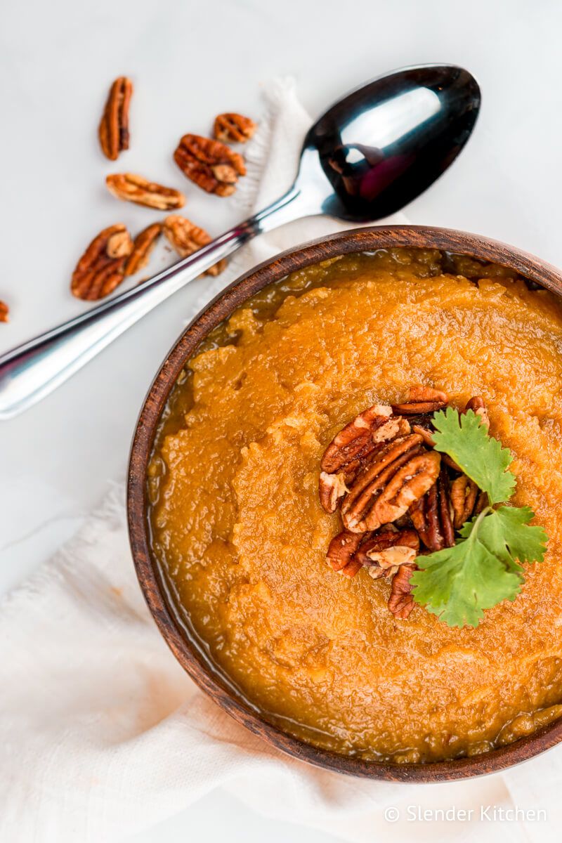 Slow Cooker Butternut Squash in a wooden bowl with walnuts and a spoon.