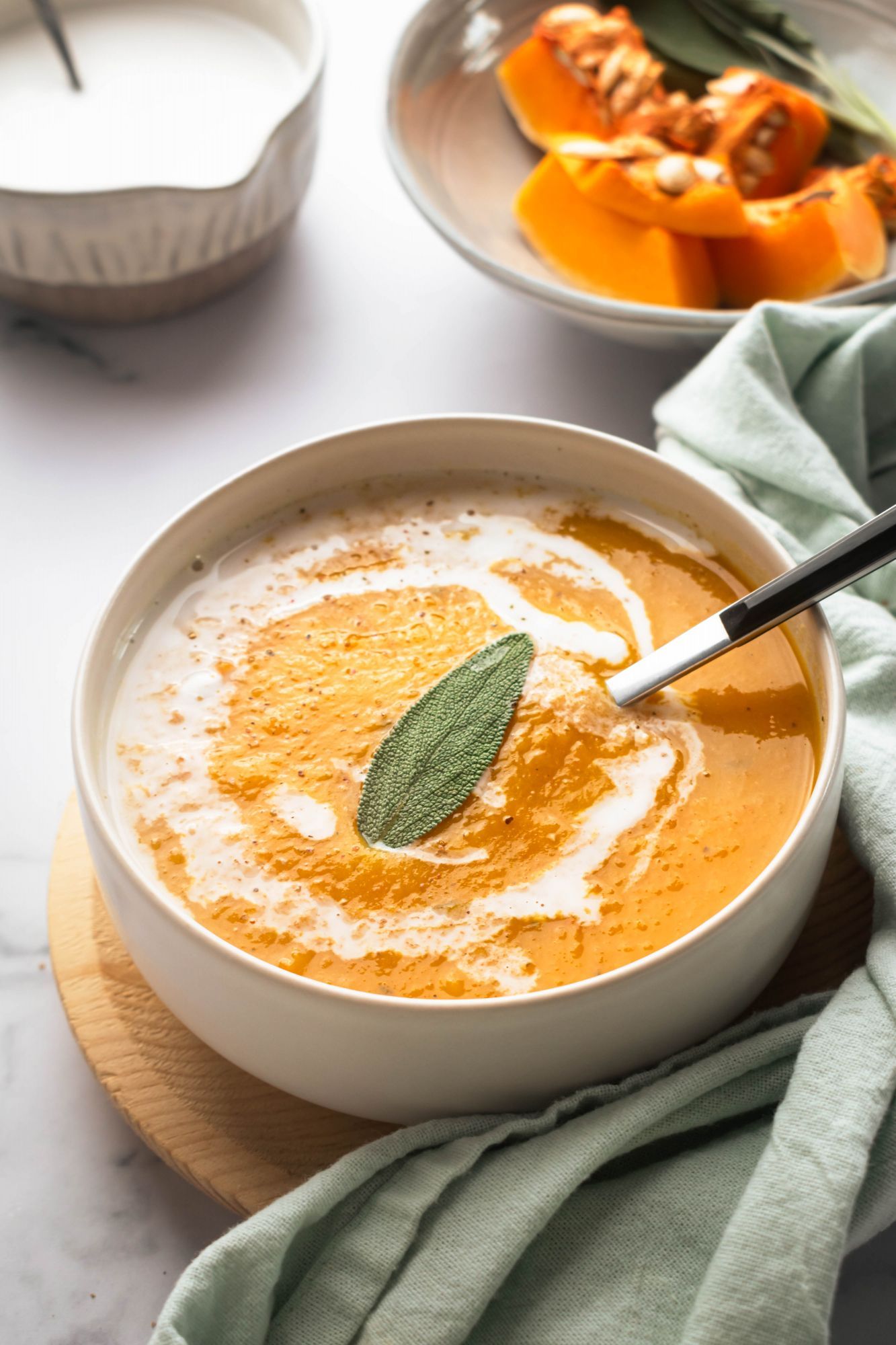 Creamy crockpot Butternut squash soup with a drizzle of coconut milk and sage on top.