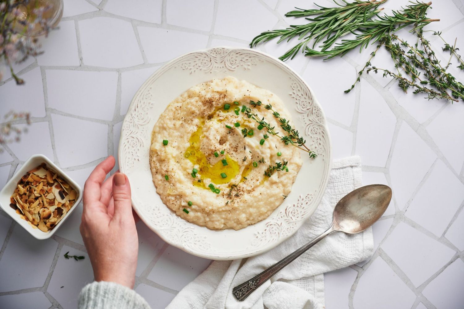 Mashed cauliflower potatoes that were cooked in the slow cooker in a white bowl with a spoon.