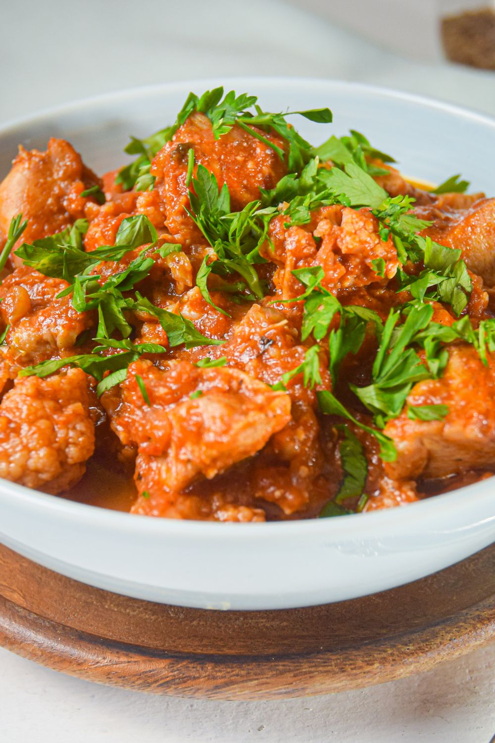 Chicken tikka masala with cauliflower in a white bowl with a spiced tomato sauce and cilantro.