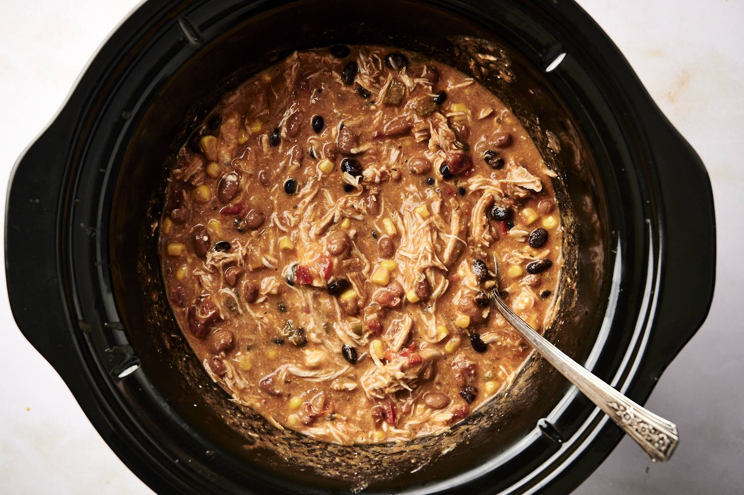 Chicken enchilada sop in the slow cooker with beans, corn, shredded chicken, and a creamy tomato broth.