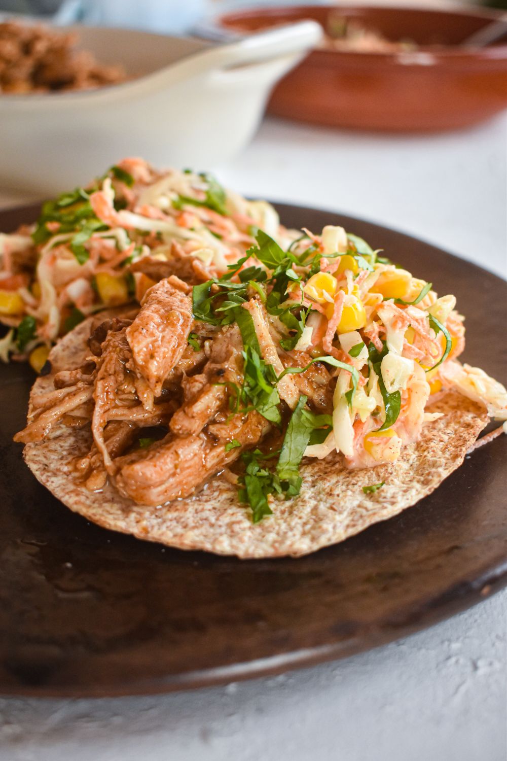 Slow cooker pulled pork wit chorizo spices on a plate with corn and cabbage slaw.