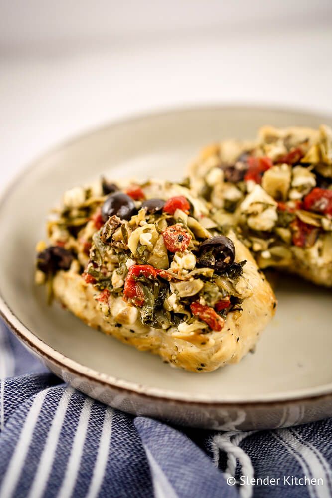 Greek chicken breasts stuffed with roasted red peppers, artichokes, feta, spinach, and olives on a plate.