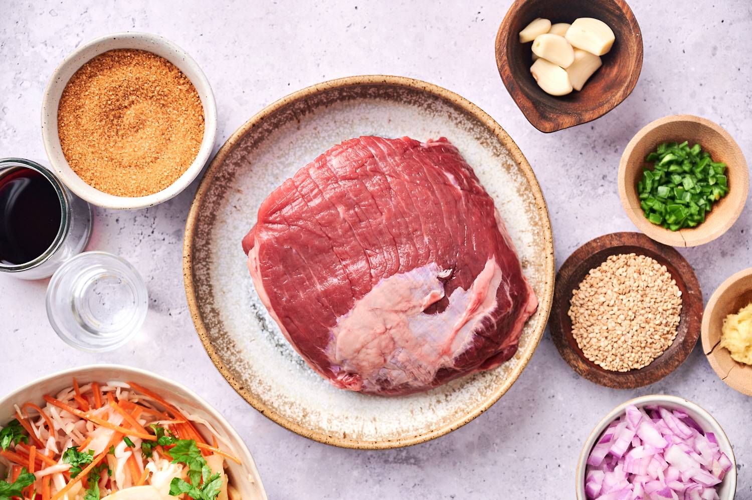Ingredients for slow cooker Korean beef tacos including beef roast, garlic, ginger, sesame seeds, soy sauce, jalapenos, onion, and slaw.