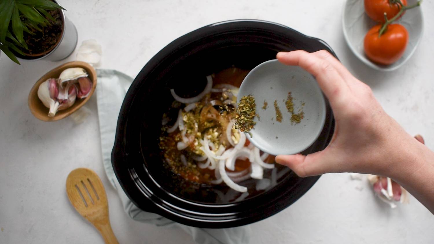 Hand pouring spices into crockpot.