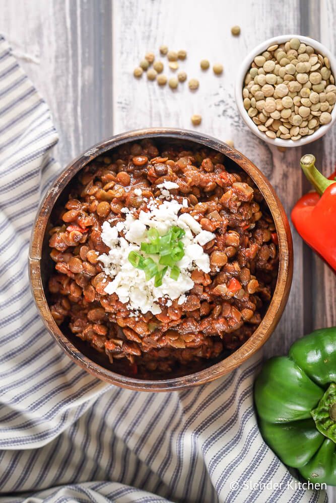 Slow Cooker Lentil Sloppy Joes with feta cheese in a wooden bowl with a blue striped napkin.