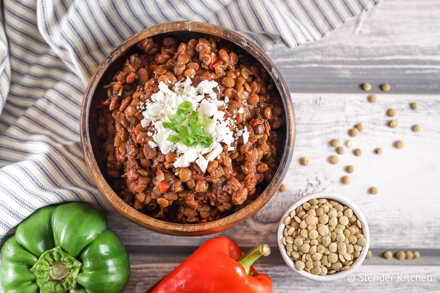 Lentil sloppy joes with cheese in a bowl with a napkin and two bell peppers.