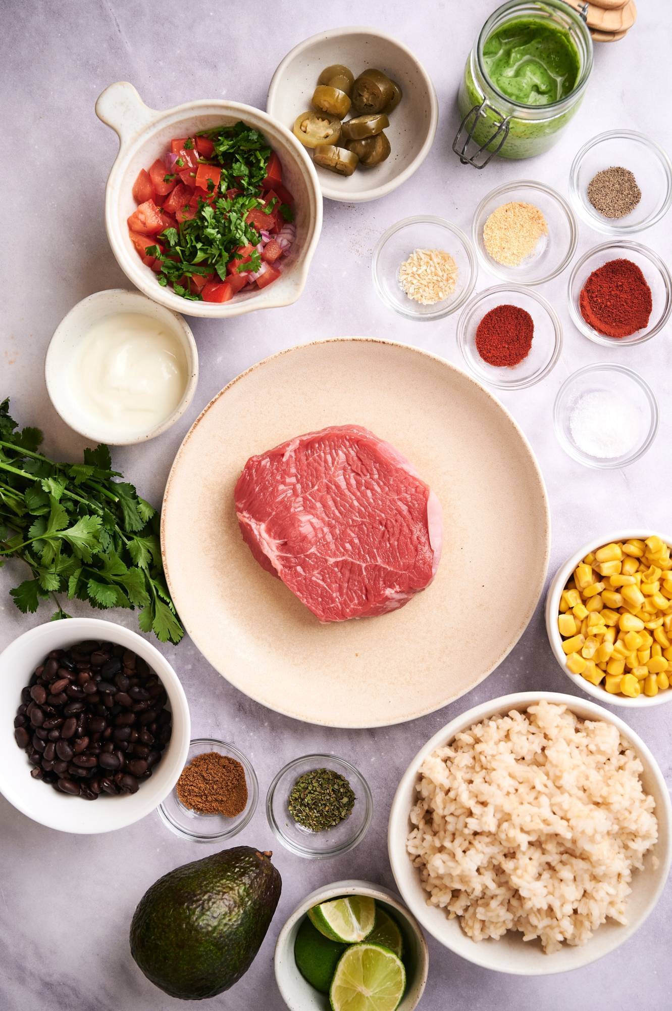 Ingredients for Southwest steak bowls including sirloin steak, rice, corn, black beans, pico de gallo, and spices.