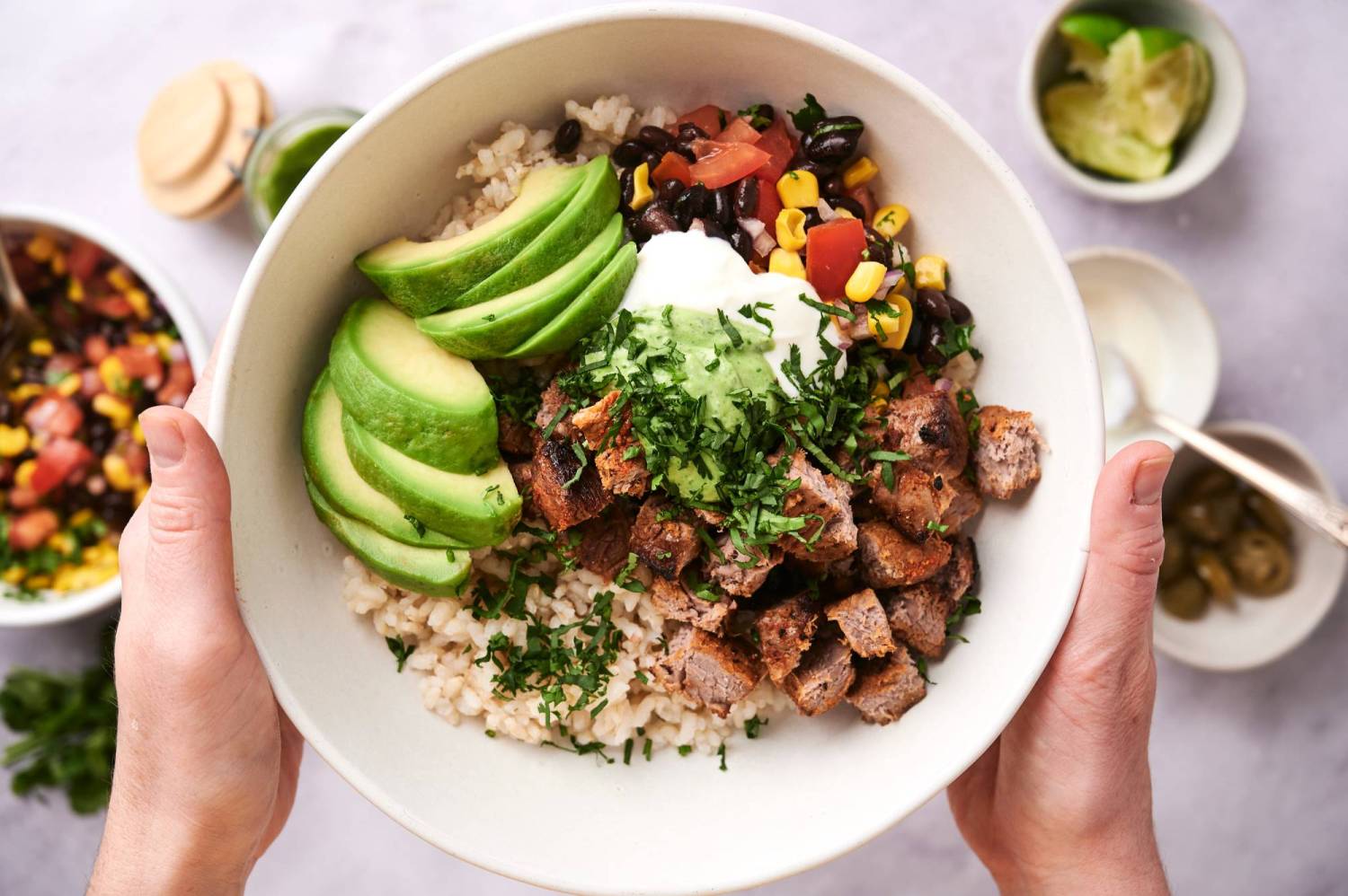 Steak rice bowls with steak bites, corn and black bean salsa, avocado, sour cream, and cilantro sauce.