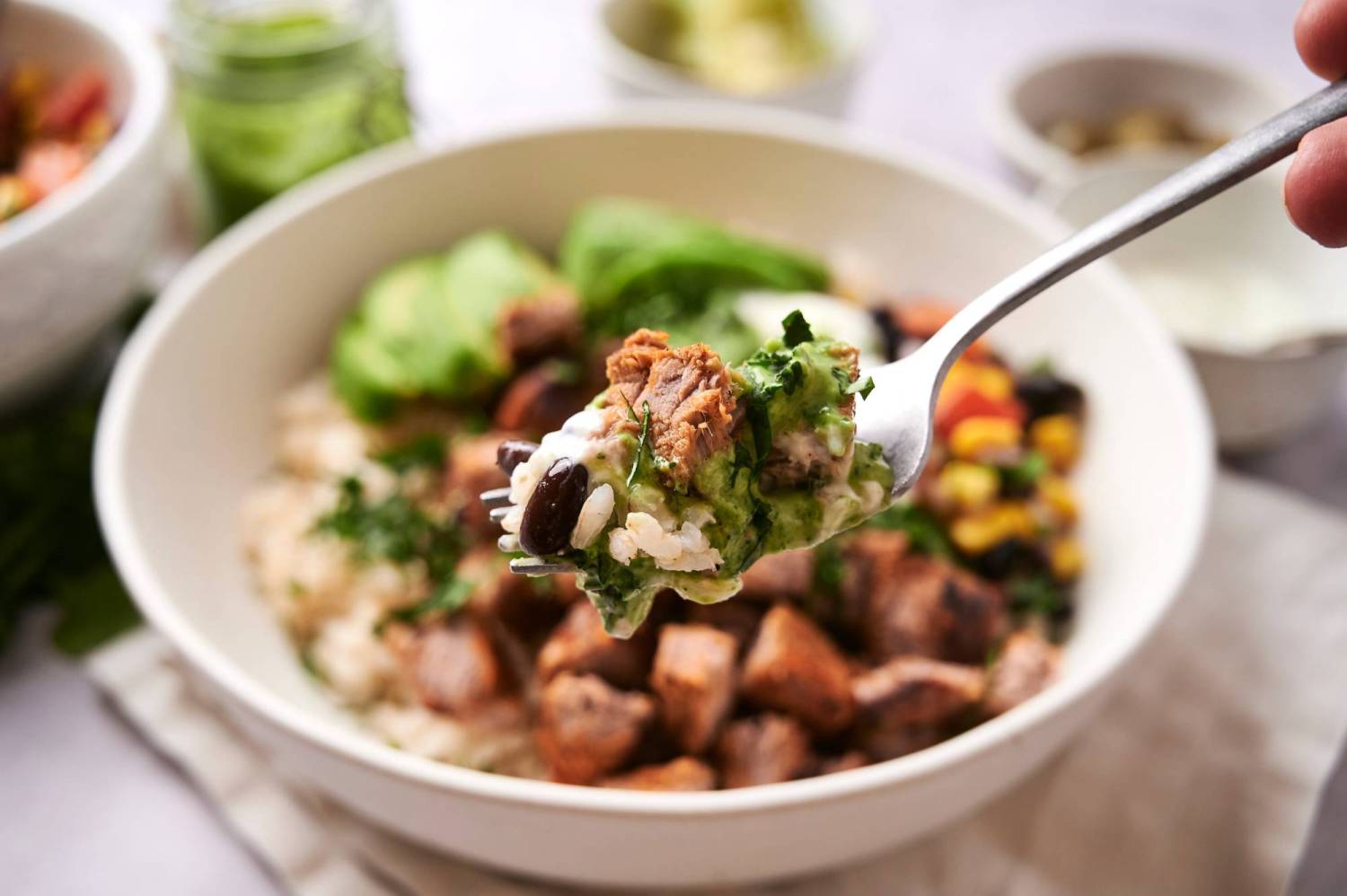 Close up of a spoonful of a southwest steak bowl with steak, rice, black beans, and cilantro sauce.