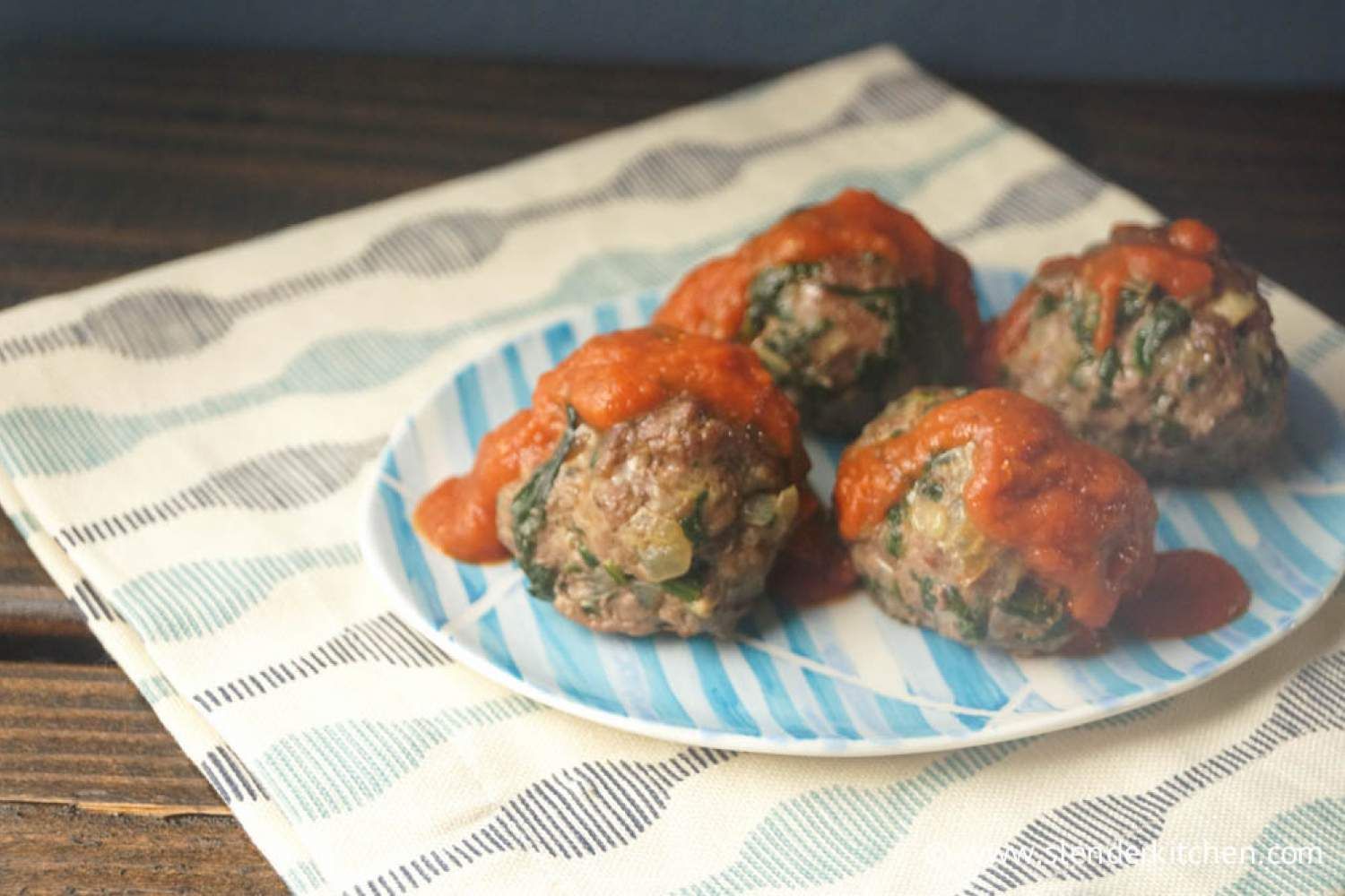 Spinach meatballs with marinara sauce on a plate.