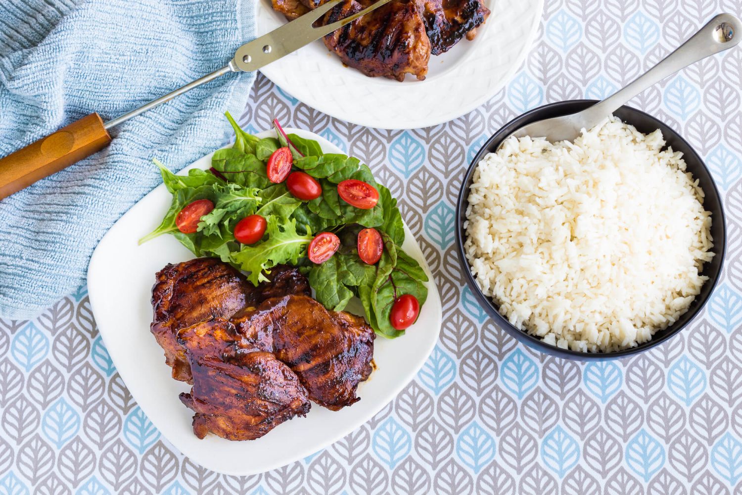 Sriracha recipe for chicken on a plate with salad and a blue napkin.